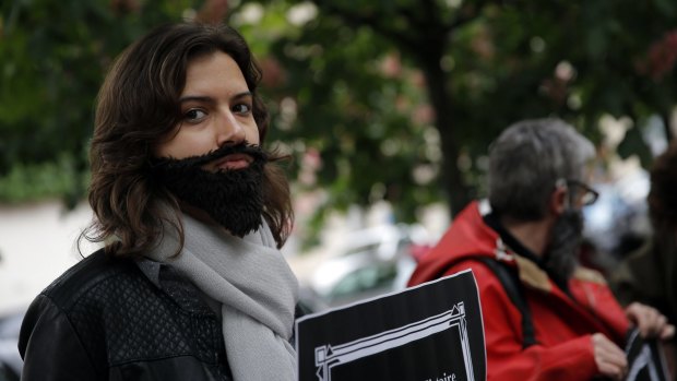A woman with a fake beard attends a Paris protest on Wednesday to demand an end to widespread sexism in French politics.