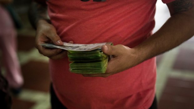 A customer counts money before purchasing animal lottery tickets in Caracas.