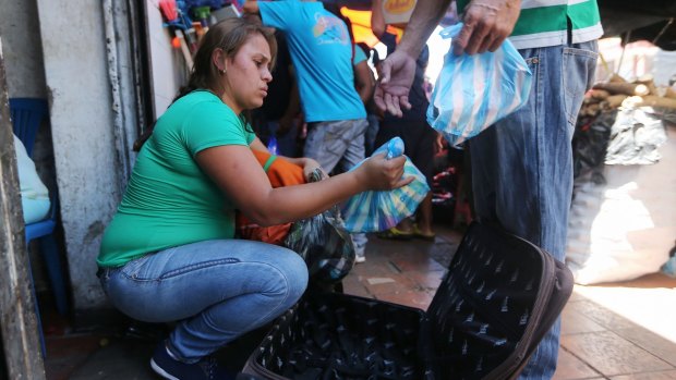 Gracy, from Venezuela, packs food she purchased in Colombia, 14 hours away, into a suitcase.
