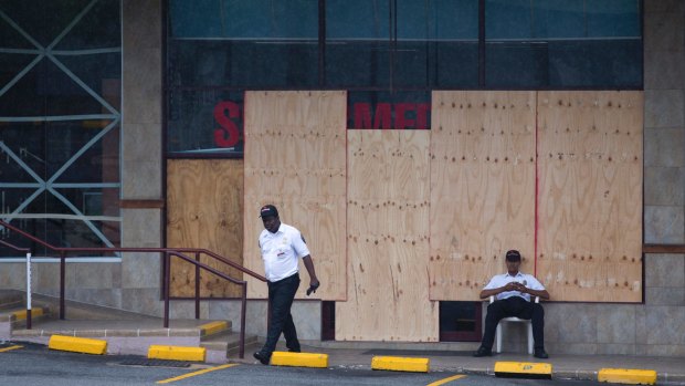 A security guard sits in front of a store that has been boarded up in preparation for the arrival of Hurricane Matthew in Kingston, Jamaica.