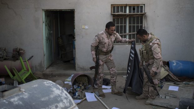 Soldiers look at an Islamic State flag inside an abandoned house in Faziliya, north of Mosul.