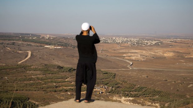 A Druze man watches fighting between forces loyal to Syrian President Bashar al-Assad and rebels in the Syrian village of Jubata al-Khashab from the Israeli-occupied Golan Heights on Sunday.