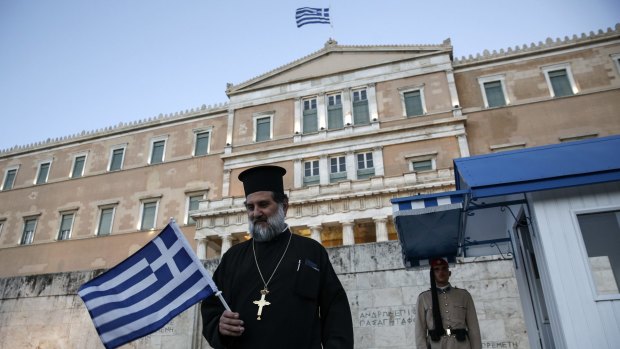 A priest walks past the presidential guard during an anti-austerity rally at Greece's parliament on Wednesday.