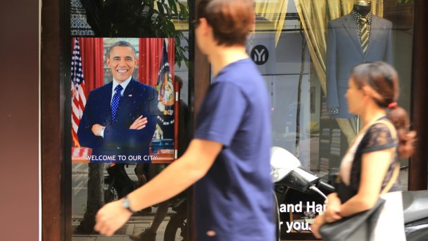 A Vietnamese couple pass a poster of US President Barack Obama hanging in a door in Hanoi.