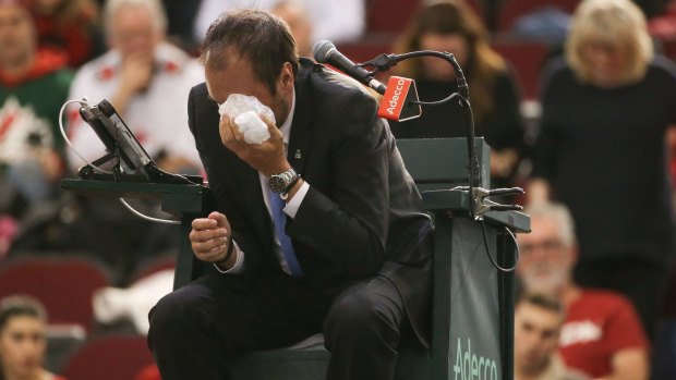 Chair umpire Arnaud Gabas reacts to getting hit in the eye with a ball.