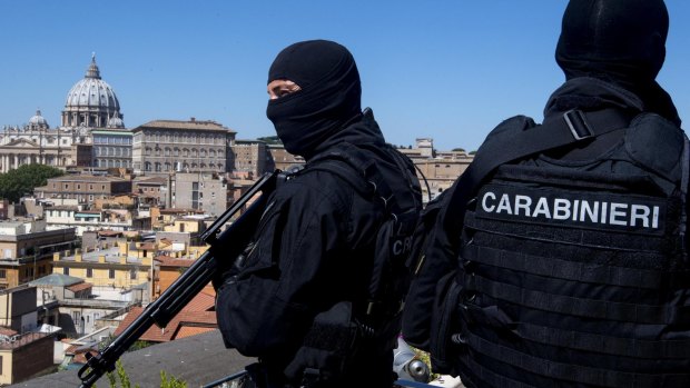 Carabinieri special unit's officers patrol the area next to St Peter's Basilica, as crowds gather.
