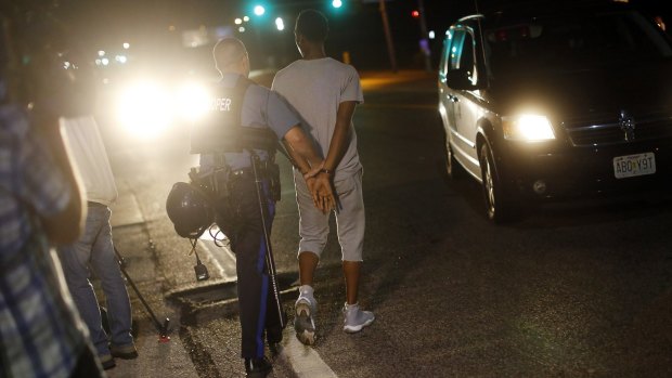 A man is handcuffed and led away by a Missouri State Trooper during demonstrations in Ferguson, Missouri, in August 2014.  
