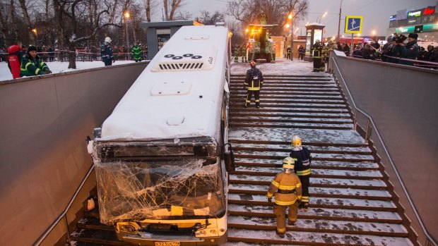 Emergency personnel work to pull a bus that crashed down subway stairs in Moscow on Monday.