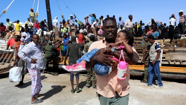 A man carries a child from a ship bearing refugees from the violence in Yemen at the port of Bosasso in Somalia's Puntland region.