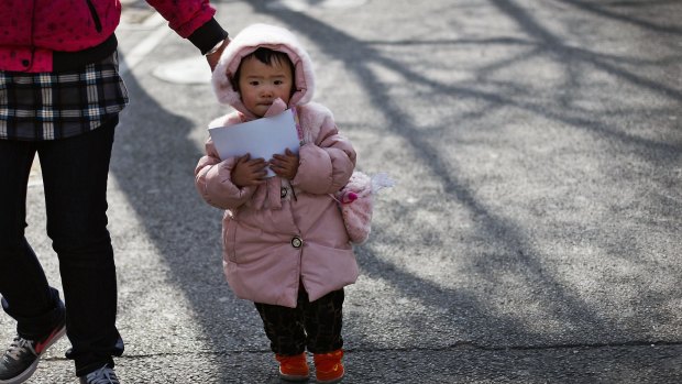 A woman leads a child in Beijing. China's ruling Communist Party announced that it will abolish the country's decades-old one-child policy.
