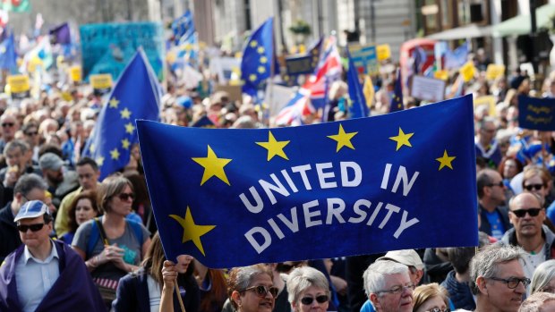 Anti-Brexit campaigners carry flags and banners as they march towards Britain's parliament in London on  Saturday March 25.