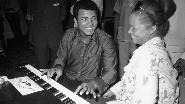 Muhammad Ali plays a few notes on the piano as singer Etta James looks on. 