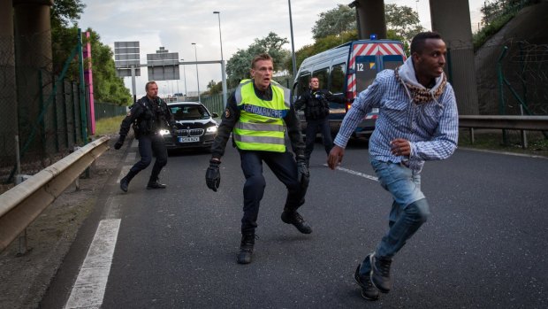 A man runs away from police near the Eurotunnel terminal in Calais. Migrants continue to risk their lives attempting to enter the Channel Tunnel in the hope of reaching England.