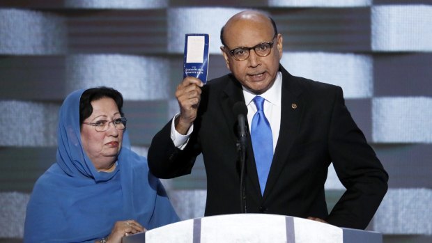 Khizr Khan, father of fallen US Army Captain Humayun Khan, holds up a copy of the US constitution at the Democratic National Convention as his wife Ghazala listens.