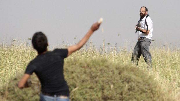 A young Palestinian throws a stone at an armed Jewish settler in 2011.