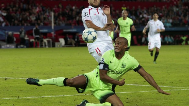 Vincent Kompany challenges for the ball with Sevilla's Ciro Immobile closing in.