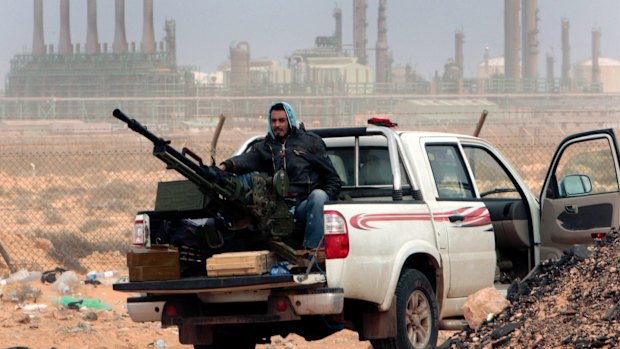 A rebel sits with an anti-aircraft weapon in front of an oil refinery in Ras Lanouf, eastern Libya. 