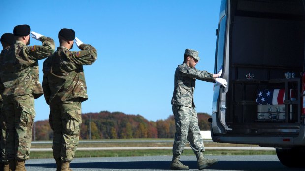 Air Force airman closes the door of a transfer vehicle containing the remains of an army solider. 