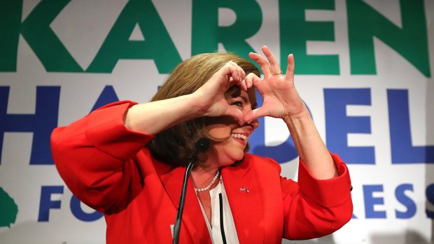 Karen Handel makes a heart symbol while making an early appearance to thank her supporters after the first returns came in during her election night in Atlanta.
