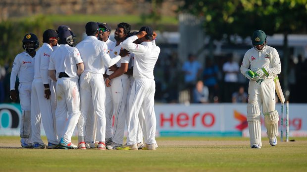 Galling: Usman Khawaja trudges off the ground in Galle during the second Test as the Sri Lankans celebrate. He was dropped for the third Test.
