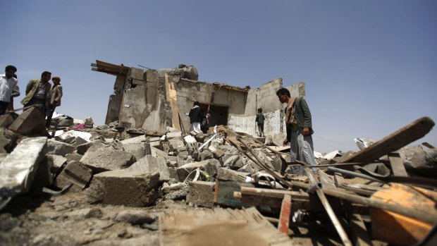 People inspect houses destroyed by a Saudi-led airstrike on the outskirts of Sanaa.