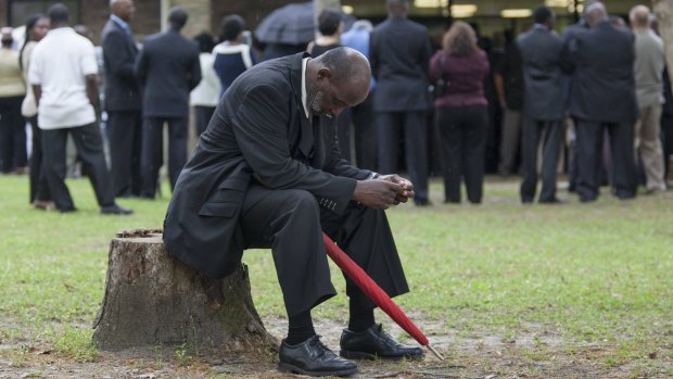 Eddie Bryan of North Charleston, South Carolina, rests on a stump outside the W.O.R.D. Ministry Christian Center in Summerville, South Carolina, during the funeral. A colleague of Scott's he was unable to find a seat for the service due to the crowds.