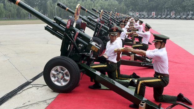 Paramilitary policemen and members of a gun salute team load cannons during a training session in Beijing.