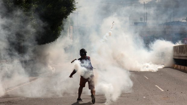 A supporter of Libre Alliance presidential candidate Salvador Nasralla returns a canister of tear gas launched by riot police in Tegucigalpa, Honduras.
