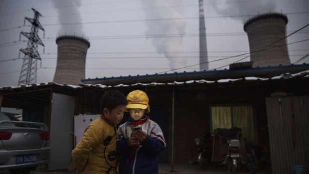 Chinese boys in front of their house next to a coal-fired power plant  in 2015. The last coal-fired power station in Beijing closed in March.