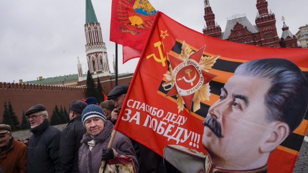 Communist party supporters carry flags with portraits of Soviet dictator Josef Stalin during a demonstration marking the 100th anniversary of the 1917 Bolshevik revolution in Red Square, in Moscow.