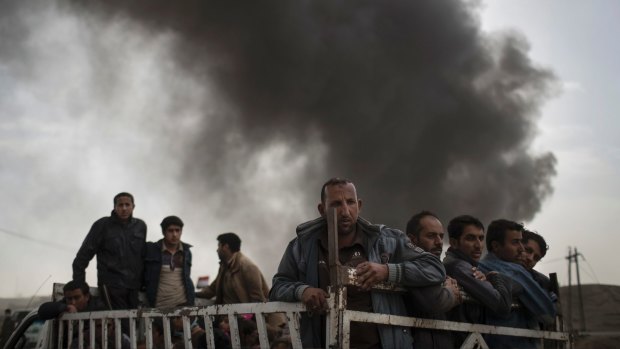 Displace people stand on the back of a truck at a checkpoint near Qayara, south of Mosul, Iraq.