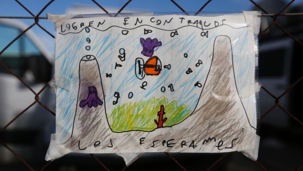 A child's drawing with the Spanish words "Find them, we wait for them" hangs on a fence at the Mar del Plata Naval Base in Argentina.