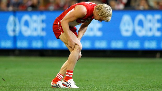 Isaac Heeney of the Swans holds his knee as he sustains an injury during Saturday night's game.