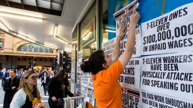 Protesters pin signs to a Melbourne 7-Eleven store.