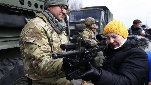 A member of the US Army's 2nd Cavalry Regiment shows a gun to a woman during the ''Dragoon Ride'' military exercise in Salociai, northern Lithuania. US troops will travel through Lithuania, the Czech Republic and on to Germany by April 1 to reinforce US allies in Eastern Europe.
