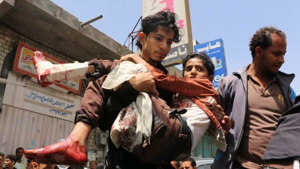 A man carries a boy injured during fighting between pro-government tribal fighters and Houthi rebels in Taiz.
