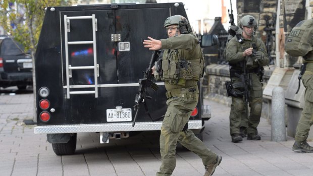 RCMP intervention team members clear the area at the entrance of Parliament hill in Ottawa.