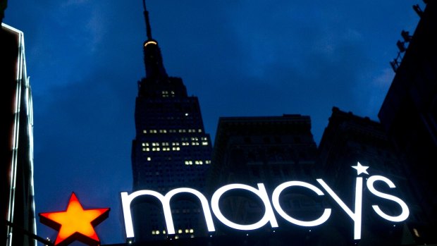 The Empire State building in the background, the Macy's logo is illuminated on the front of the department store in New York. 