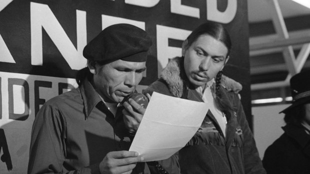 Banks, left, reads an offer by the US government seeking to effect an end to the Native American takeover of Wounded Knee.
