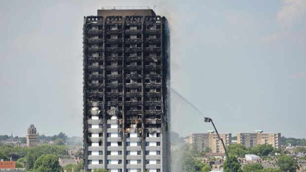 Firefighters spray water onto the 24-storey apartment block in west London on Wednesday.