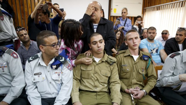 Israeli soldier Elor Azaria, centre seated, in court charged with manslaughter by the Israeli military. His father prays behind him. 