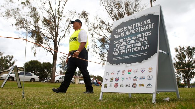 A security guard patrols a Junior League match at Allsopp Oval in Penrith in 2015, as a sign warns parents to keep calm.