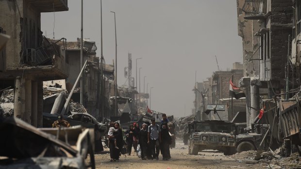 Iraqi people carrying what possessions they can hold escape from Islamic State.