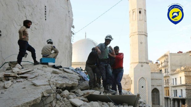 A photo provided by the Syrian group known as the White Helmets shows their personnel carrying a body after air strikes hit the Bustan al-Basha neighbourhood in Aleppo.