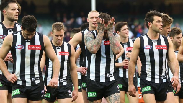 The Magpies look dejected after losing the game to the Demons.