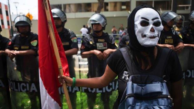 A protester in mask holds a Peruvian national flag during a rally against the Trans Pacific Partnership in Lima, Peru in November 2016.