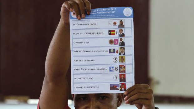 An election worker holds up a ballot during the presidential election's vote counting at a polling station in Dili, East Timor.