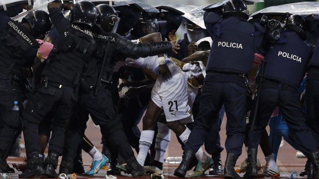 Riot police shield Ghana's John Boye (21) and teammates from objects thrown by Equitorial Guniea fans 