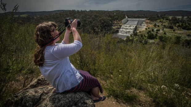 Photographer Bethany Roberts catches photos as Googong dam spills over the walls after recent rains. 