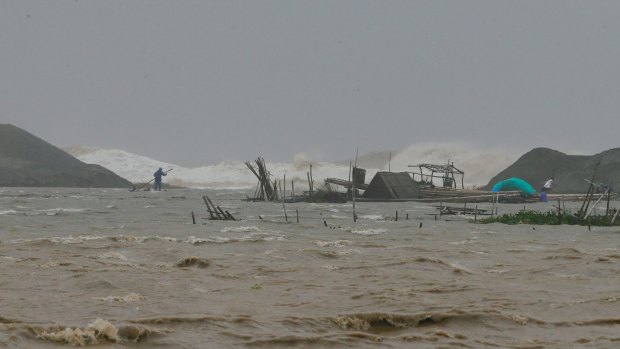 A Philippine fisherman works on his destroyed fish cages amidst huge waves brought about by Haima.